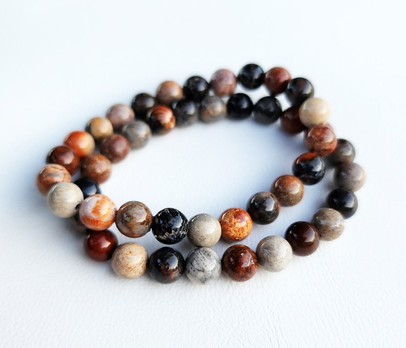 Puede incluir: Un brazalete de cuentas multicolores con cuentas marrones, negras y blancas. El brazalete est&aacute; hecho de piedra natural y tiene un aspecto r&uacute;stico.