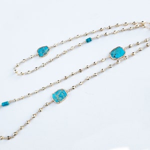 May include: A gold chain necklace with three turquoise stones. The chain is made of small, round beads.