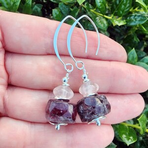 May include: A pair of silver dangle earrings with a clear quartz and a deep purple amethyst stone.