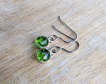 Peut inclure: Une paire de boucles d'oreilles en argent avec des gouttes de pierres précieuses vertes. Les boucles d'oreilles ont un design simple et sont parfaites pour tous les jours.