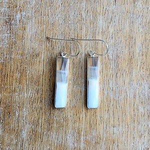 May include: A pair of silver dangle earrings with white and brown agate stone rectangular drops.