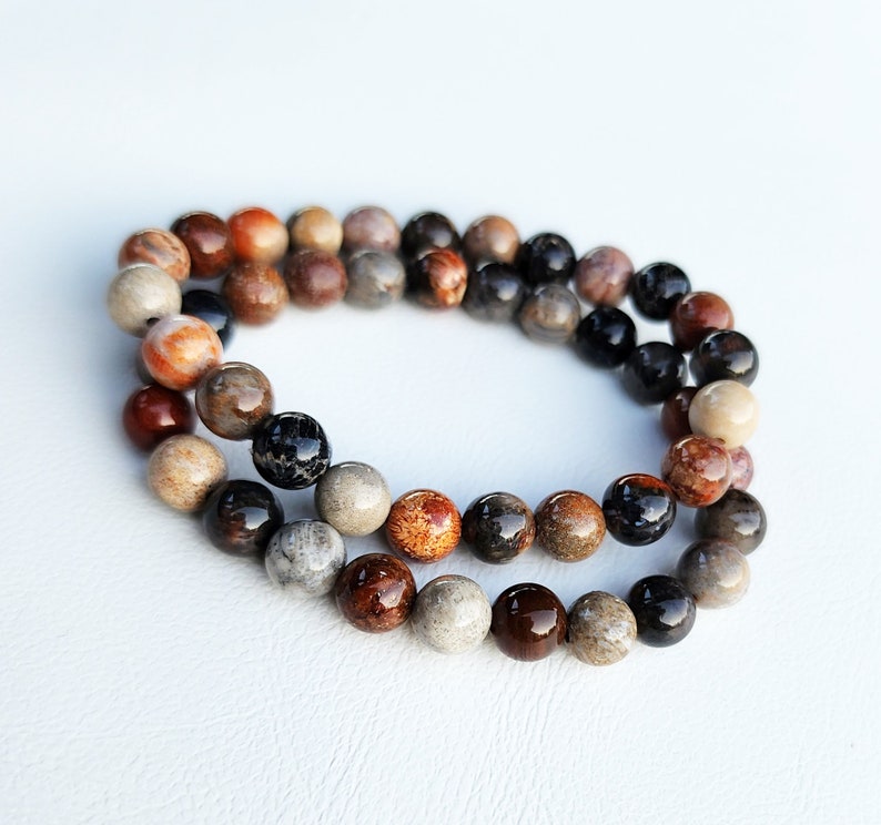 Puede incluir: Un brazalete de cuentas multicolores con cuentas marrones, negras y naranjas. El brazalete est&aacute; hecho de piedra natural y tiene un aspecto r&uacute;stico.