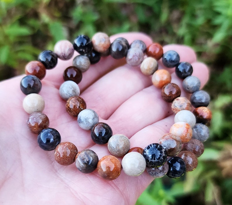 Puede incluir: Un brazalete de cuentas multicolores con cuentas marrones, beige, naranja y negras. El brazalete est&aacute; hecho de piedra natural y tiene un aspecto terroso &uacute;nico.