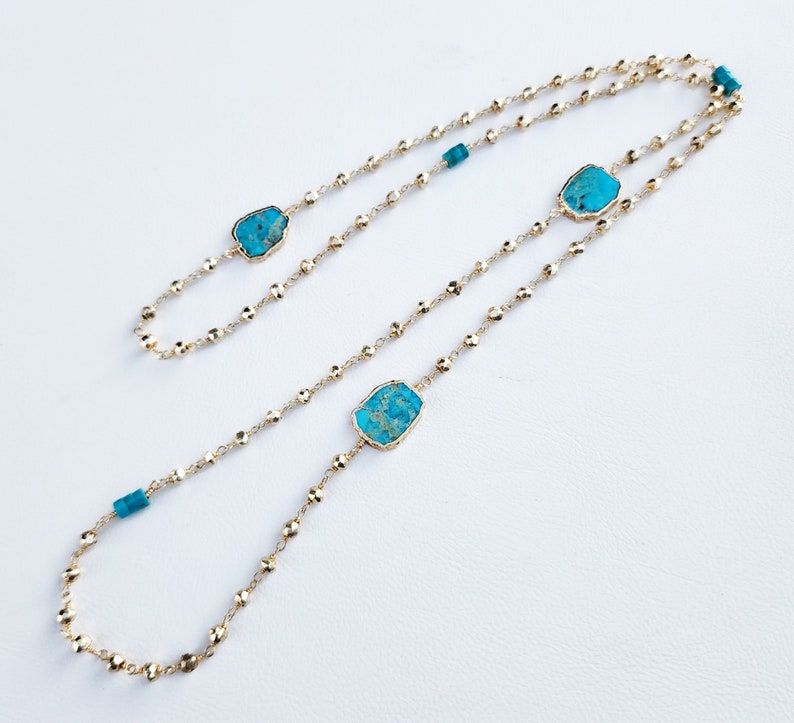 May include: A gold chain necklace with three turquoise stones. The stones are irregular in shape and have a mottled pattern.