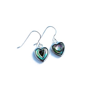 May include: A pair of silver heart-shaped earrings with iridescent abalone shell inlays. The earrings have a simple hook closure.