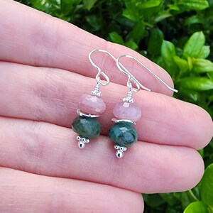 May include: A pair of silver earrings with pink and green gemstone beads. The earrings have a simple design and are perfect for everyday wear.