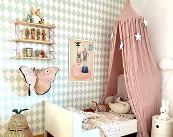 Könnte beinhalten: Kinderzimmer mit weißem Bett, rosa Baldachin und einer Wand, die mit einem großen Schmetterling und einem Poster dekoriert ist. Der Raum hat eine hellgrüne und weiße Rautenmuster-Tapete, einen weidenförmigen Korb und einen weißen Nachttisch.