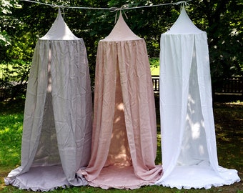 Puede incluir: Tres tiendas de campaña con dosel hechas de tela transparente en gris, rosa y blanco. Las tiendas están colgadas de una cuerda y tienen un borde con volantes.