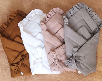 Könnte beinhalten: Vier Baby-Swaddles in den Farbtönen Braun, Weiß, Rosa und Grau. Jeder Swaddle hat ein gestepptes Design, einen gerüschten Rand und einen Schleifenverschluss. Die Swaddles sind aus weichem Stoff und für Neugeborene konzipiert.