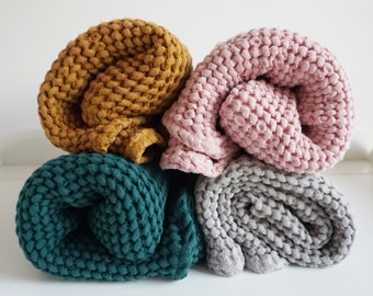 Könnte beinhalten: Vier gerollte Waffelstrickdecken in Senfgelb, Staubrosa, Türkis und Grau. Die Decken sind eng gerollt und zeigen das strukturierte Gewebe des Stoffes. Die sanften Farben schaffen eine gemütliche und einladende Ästhetik, ideal für die Inneneinrichtung.