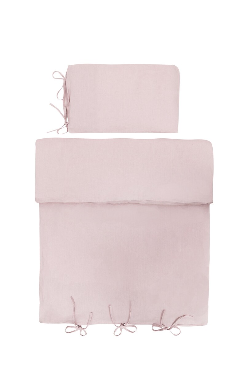 May include: A pink linen duvet cover and pillow sham set with ties at the corners.