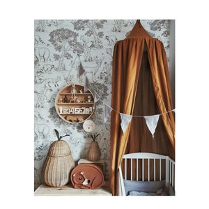 May include: A nursery scene with a brown canopy over a white cot. A round wooden shelf displays wooden toys and numbers. A pear-shaped woven basket and a sleeping bear nightlight are on a wooden surface. The wallpaper has a black and white forest scene.