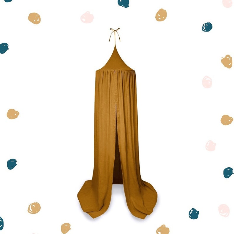 May include: Mustard-coloured canopy bed with a conical top and flowing fabric. The canopy is suspended from a single point and has a split front. The background is white with scattered colourful dots.