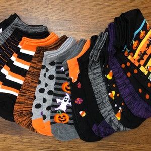 Puede incluir: Un conjunto de 12 calcetines de tobillo con tem&aacute;tica de Halloween con varios patrones que incluyen calabazas, fantasmas, ma&iacute;z dulce, murci&eacute;lagos y rayas. Los calcetines son negros con detalles en naranja, blanco y morado.