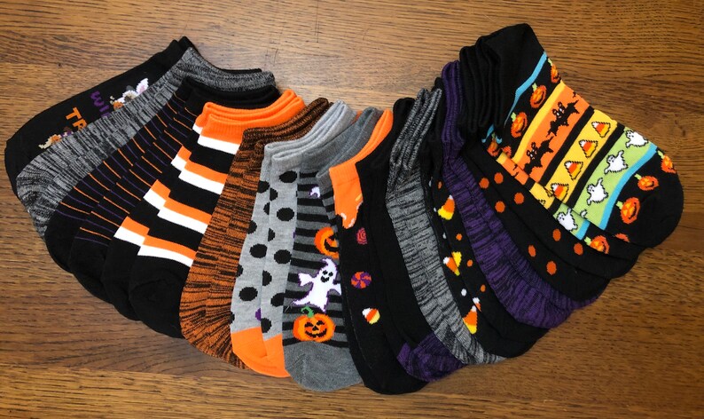 Puede incluir: Un conjunto de 12 calcetines de tobillo con tem&aacute;tica de Halloween con varios patrones que incluyen calabazas, fantasmas, ma&iacute;z dulce, murci&eacute;lagos y rayas. Los calcetines son negros con detalles en naranja, blanco y morado.