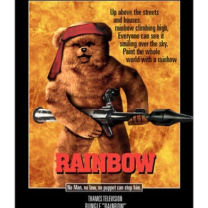 May include: A poster for the children's television show "Bungle" featuring a brown teddy bear holding a large black and silver gun. The poster has the text "Bungle "Rainbow"" and "No Man, no law, no puppet can stop him."