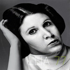 May include: Black and white portrait of a woman with dark hair and a serious expression. The text "LEIA 77" is printed in white and green on the bottom of the image.
