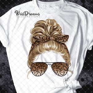 May include: A white t-shirt with a graphic of a woman with blonde hair in a messy bun, wearing leopard print sunglasses and a headband. The text "KrisDreams Illustrations" is printed on the shirt.