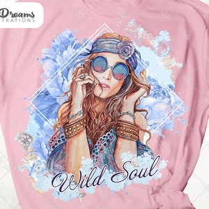 May include: A pink t-shirt with a watercolor design of a woman with long brown hair wearing a headband and sunglasses. The design includes blue flowers and the text "Wild Soul".