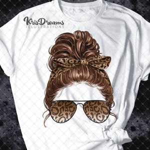 May include: A white t-shirt with a graphic of a woman with brown hair in a messy bun wearing leopard print sunglasses and a headband. The text "KrisDreams Illustrations" is printed on the shirt.