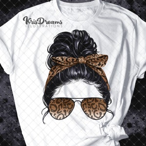 May include: White t-shirt with a graphic of a woman with black hair in a messy bun, wearing leopard print sunglasses and a leopard print headband. The text "KrisDreams Illustrations" is at the top of the shirt.