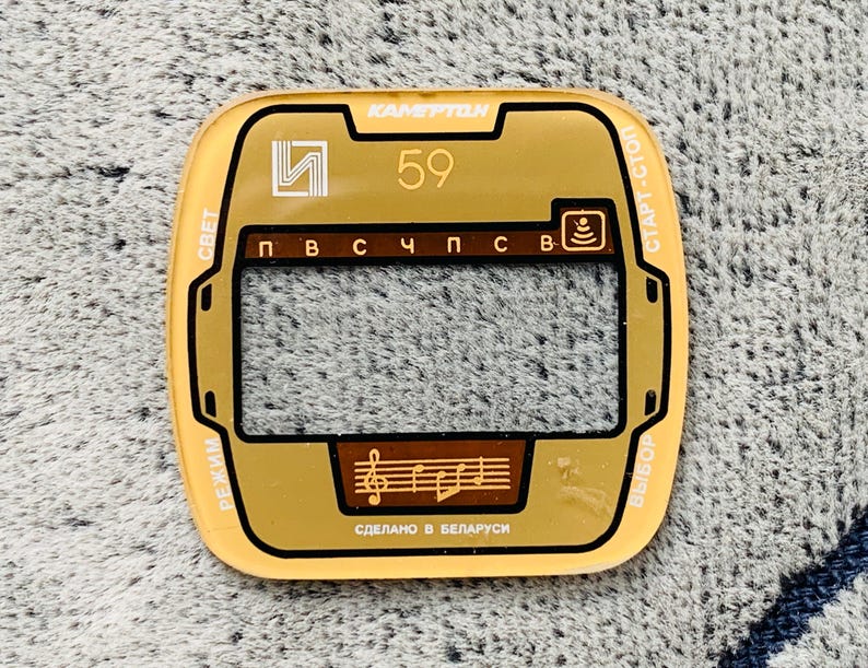 May include: A vintage gold-colored radio faceplate with the text "KAMERTON" at the top. The faceplate has a rectangular window, a musical note graphic, and the number "59". The text "Made in Belarus" is also visible.