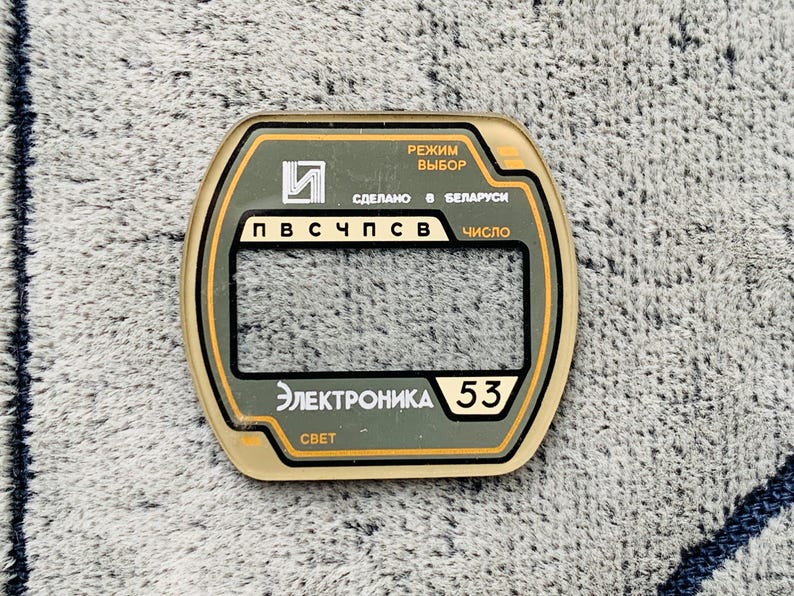 May include: A rectangular electronic component with a clear window and text in Russian. The component has a green and gold color scheme, with the text "Электроника 53" and "СВЕТ" visible.