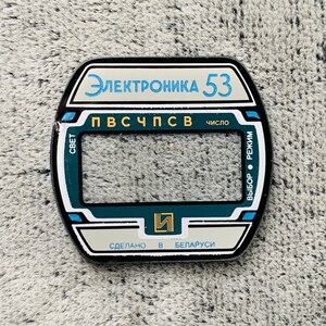 May include: A rectangular, black and white electronic device component with the text "Электроника 53" in blue. The component has a teal and white border and includes Cyrillic text and the words "Made in Belarus".