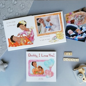 May include: A children's book titled "Daddy, I Love You!" with illustrations of a father and child. The book is open to a page with the text "You even change my dirty nappy." and an illustration of a father changing a baby's diaper. The next page shows the text "You'll do anything to make me happy." and an illustration of a baby sitting in a high chair. The book is surrounded by photos of a baby in different settings, including a car seat and a high chair. The photos are labeled "6 x 4 PHOTOS".