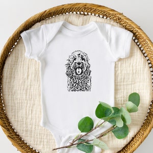 May include: White baby onesie with a black and white illustration of a dog on the front.