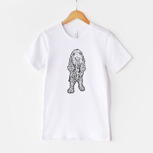 May include: White t-shirt with a black and white line drawing of a cocker spaniel dog.