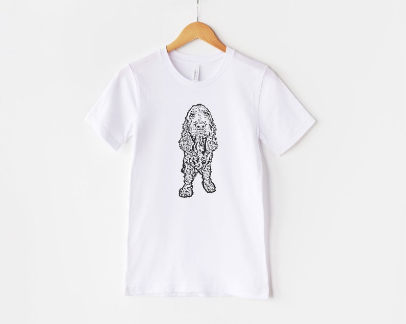 May include: White t-shirt with a black and white line drawing of a cocker spaniel dog.