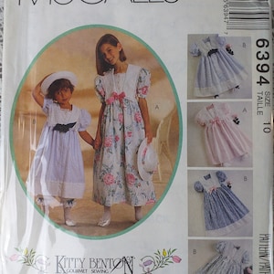 May include: A McCall's sewing pattern envelope featuring two young girls in dresses. The dresses are in various pastel colors with floral and lace details. The envelope includes the text "McCall's" and "Kitty Benton Gourmet Sewing".