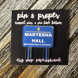 May include: Blue enamel pin with a white sign that reads "Marteena Hall Mathematics & Physics". The pin is on a black background with the text "pin & proper enamel pins & pin back buttons" and "etsy shop: paperoybrandi".