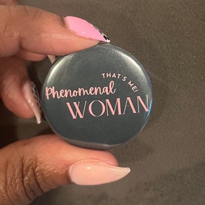 May include: A gray button with the text "That's Me! Phenomenal Woman" in pink and black lettering.