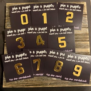 May include: A set of three ceramic mugs with a speckled, matte finish. The mugs are in shades of cream, light gray, and dark gray. Each mug has a simple, minimalist design, perfect for coffee or tea.