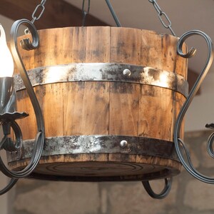 May include: A rustic wooden barrel chandelier with a black metal frame and four light bulbs. The chandelier has a distressed wood finish and a simple design.