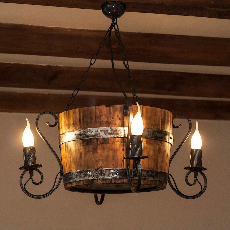 May include: A rustic wooden barrel chandelier with a black metal frame and three light bulbs. The chandelier is hanging from a chain.