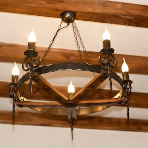 May include: A black wrought iron chandelier with wooden accents and five light bulbs. The chandelier is hanging from a wooden ceiling.