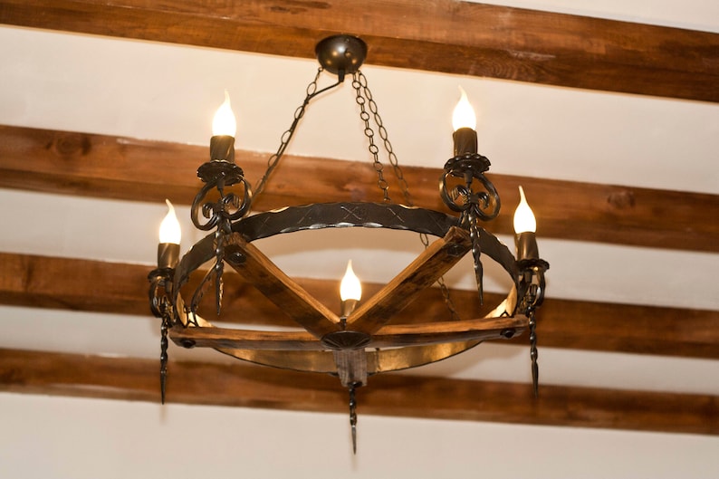 May include: A black wrought iron chandelier with wooden accents and five light bulbs. The chandelier is hanging from a wooden ceiling.