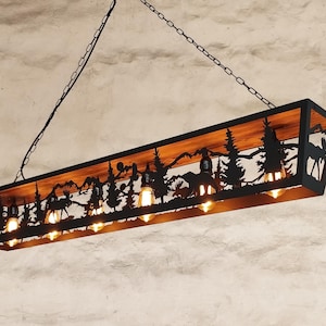 May include: A black metal chandelier with a wooden shelf and a cut-out design of a forest scene with mountains, trees, and animals. The chandelier has eight light bulbs.