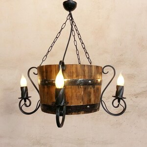 May include: A rustic wooden barrel chandelier with a black metal frame and three light bulbs. The chandelier is hanging from a chain.