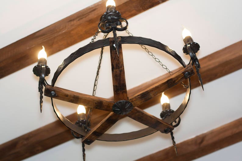 May include: A rustic chandelier with a circular metal frame and wooden spokes. The chandelier has five light bulbs and a chain hanging from the top.