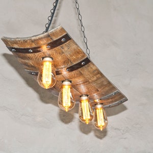 May include: A rustic wooden chandelier with four Edison bulbs hanging from a chain. The chandelier is made from a repurposed wine barrel stave.