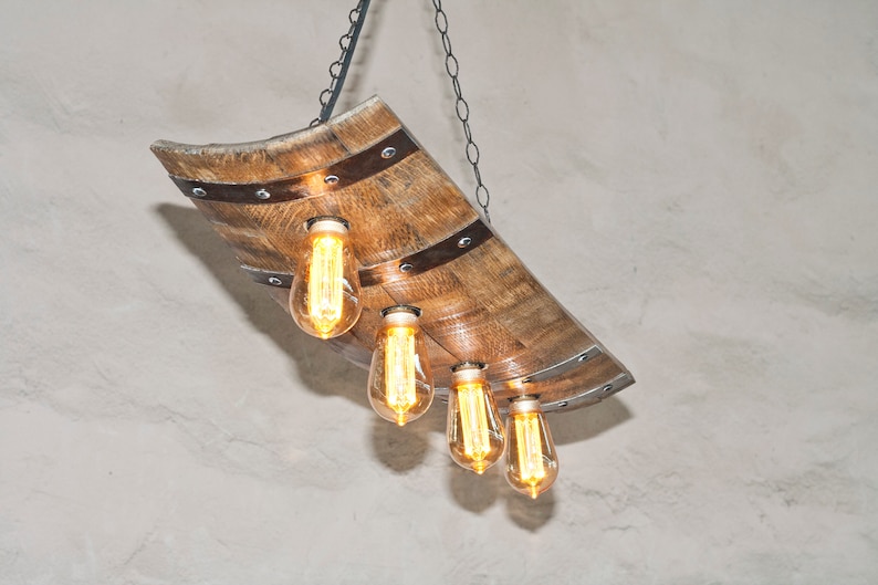 May include: A rustic wooden chandelier with four Edison bulbs hanging from a chain. The chandelier is made from a repurposed wine barrel stave.