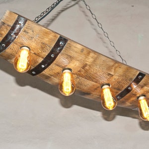 May include: A rustic wooden chandelier made from a reclaimed wine barrel with four exposed light bulbs. The chandelier has a metal chain and is hanging from a ceiling.