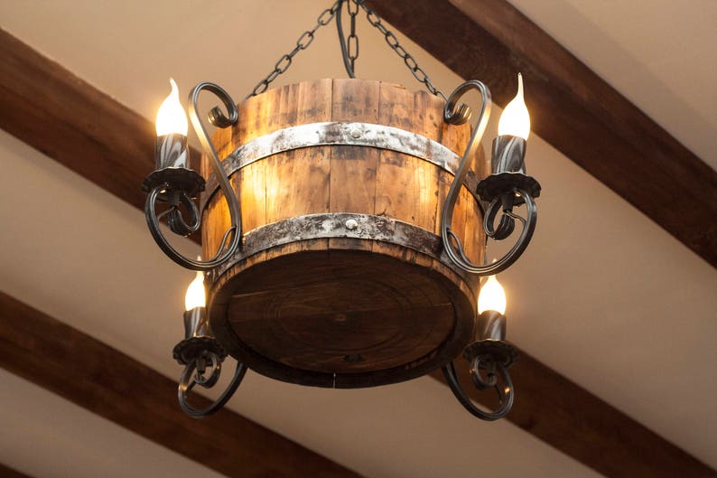 May include: A rustic wooden barrel chandelier with a black metal frame and multiple light bulbs. The chandelier is hanging from a chain.