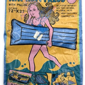 May include: Vintage air mattress in a plastic package. The package features a cartoon illustration of a woman carrying a blue air mattress. Text on the package reads "AIR MATTRESS WITH PILLOW" and "CUT SIZE 72"X27"". Includes illustrations of the mattress in use.