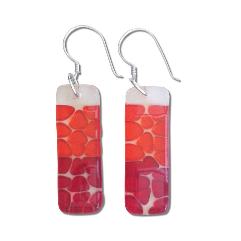 May include: Red and orange glass earrings with a geometric pattern. The earrings are rectangular and have silver hooks.