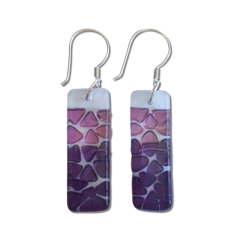 May include: A pair of silver earrings with rectangular purple glass pendants. The glass is made up of small, irregular shapes that create a gradient effect from light pink to dark purple.